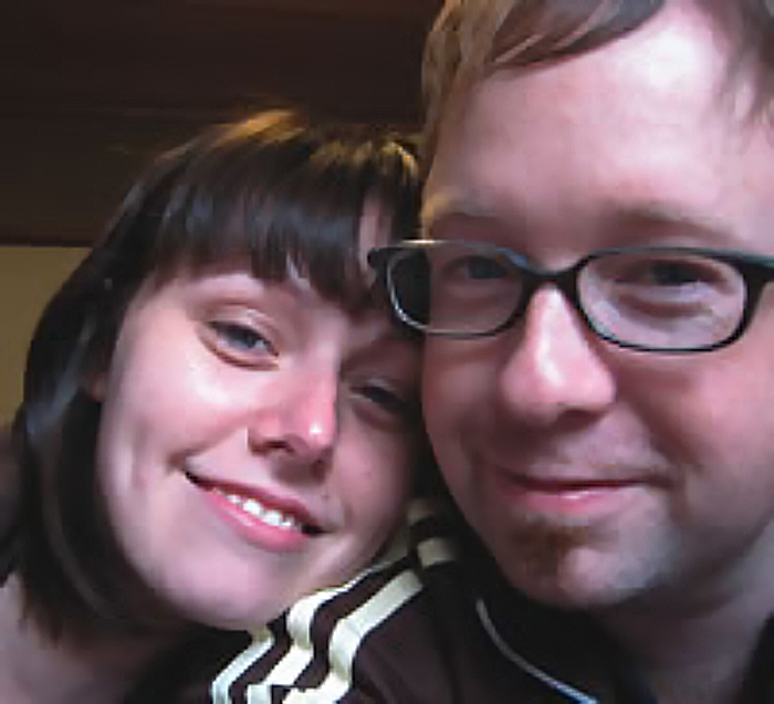 Closeup headshot of Laurie Stewart and Chris McGarvey. Chris is wearing dark-framed glasses, and Laurie is leaning her head on Chris's shoulder.