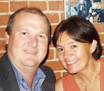 Close-up headshot of Greg Evans and Ronda Wabie in front of a red brick wall