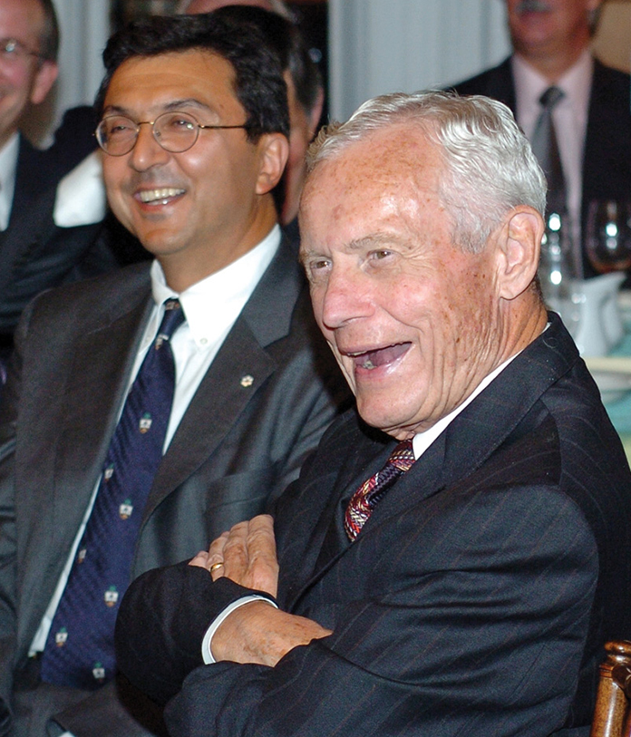 Warren Goldring (right) sitting with his arms crossed, next to U of T President David Naylor