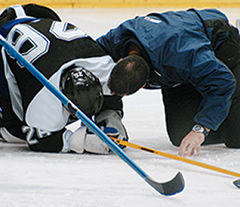 Photo of an injured hockey player being checked on by a coach.