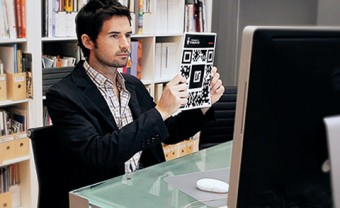 Photo of a man holding a sheet of QR codes