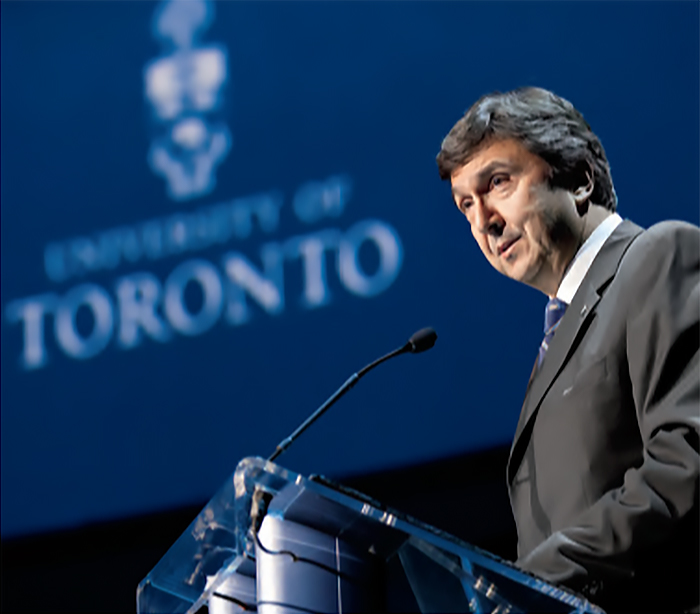 David Naylor standing at a podium, giving an address, with the University of Toronto logo projected on a screen behind him