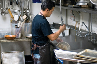 A man working in a kitchen washing dishes.