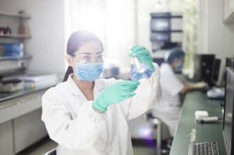 Photo of a doctor or chemist in a lab mixing chemicals.
