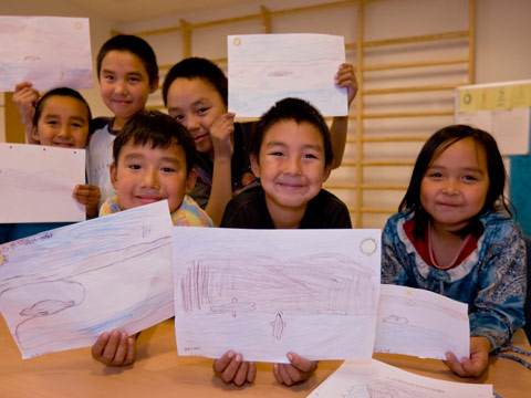 Indigenous children show their illustrations from class.
