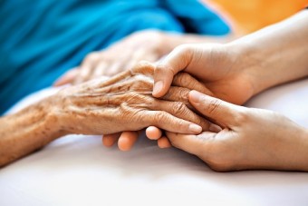 Photo of young hands holding an elderly person's hand.