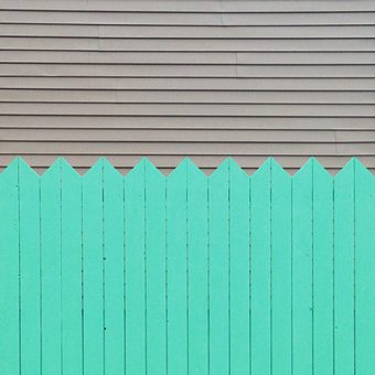 Photo of light grey horizontal lines in the upper half and light green, vertically lined picket fence in the bottom half