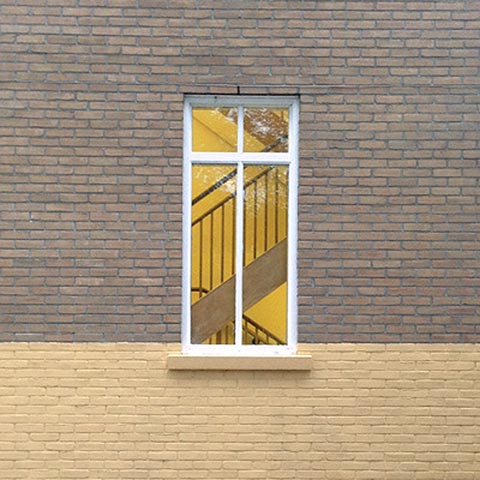 Photo of a window showing a staircase and surrounded by a brick wall