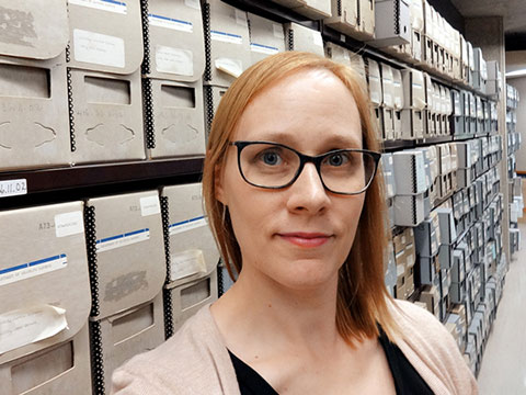Photo of Karen Suurtamm in front of shelves of archived records