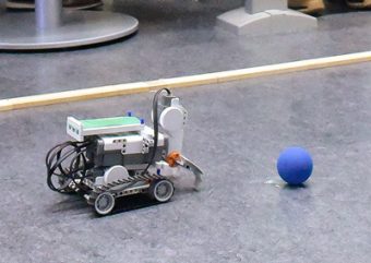 Photo of a small robot with wheels in front of a ball