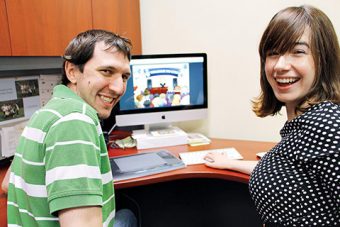 Photo of Chris Primerano and Heather Shanahan sitting in front of a computer screen displaying the game