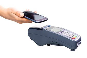 Photo of a hand holding a cell phone over a portable card machine