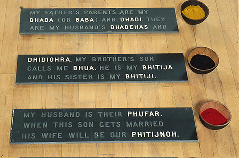 Photo of artwork by Sarinda Dhaliwal, “Punjabi Sheets #2: Family Tree," with each name of the family tree on slates with a bowl containing different coloured powders on the right