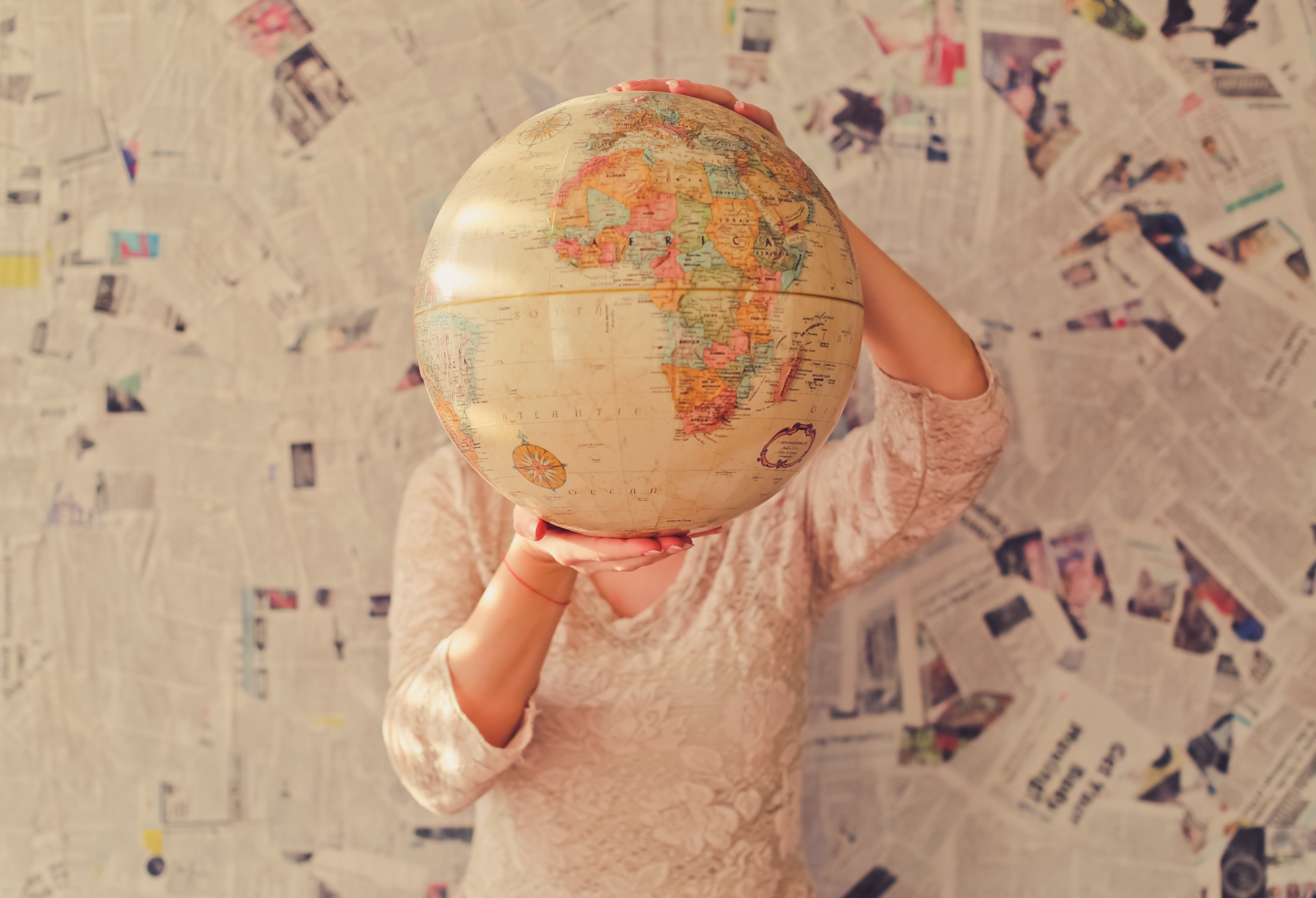 Photo of a person holding a globe in front of themselves.