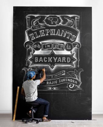 Photo of Rajiv Surendra drawing the cover of "The Elephants in My Backyard" on a large chalkboard