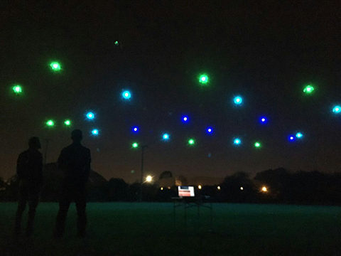 Night sky lit up by drones with blue and green dots of light