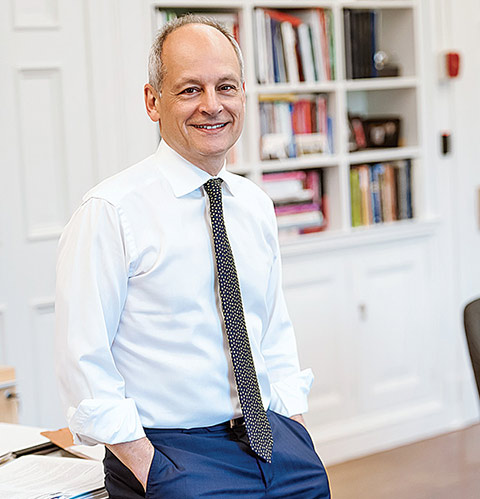 Meric Gertler leaning on a desk in his office