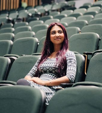 Muhaddisah Batool sitting in a seat in an empty theatre