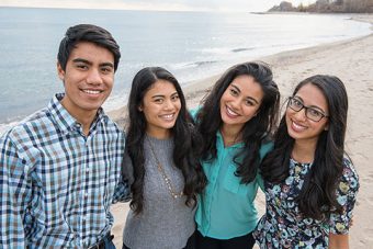 Photo of the Syed siblings standing on a beach, smiling at the camera.