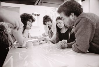 A group of students huddled over a classroom table