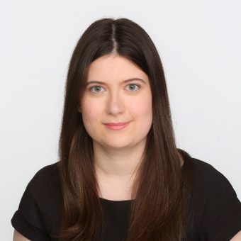 Studio headshot of Tara Deschamps wearing a black shirt in front of a white background