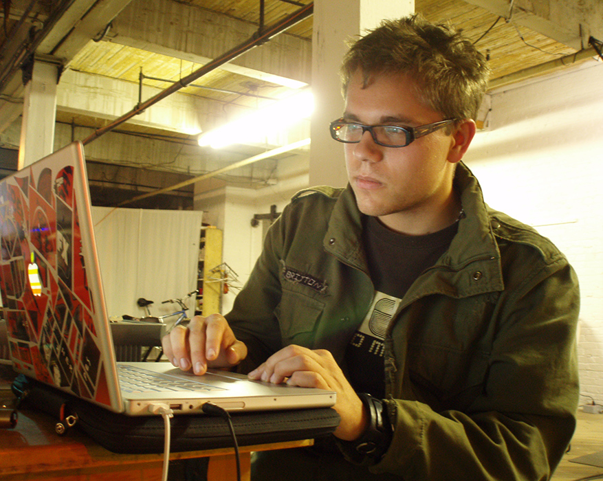 Eliot Britton operating his laptop in a large studio space