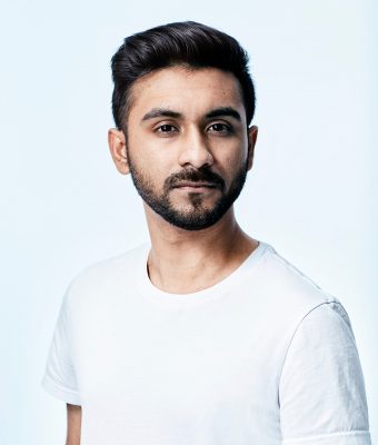 Photo of Tahmid Khan in a white T-shirt looking at the camera with a serious expression, shot in a studio against a bluish white background