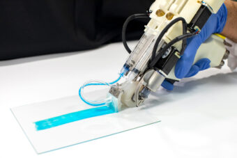 Researcher operating the 3D bioprinter, placing a blue strip on a surface