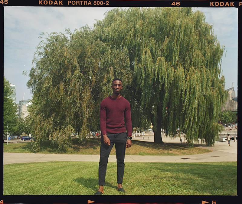 Ernest Nyarko standing on grass with a large willow tree in the background