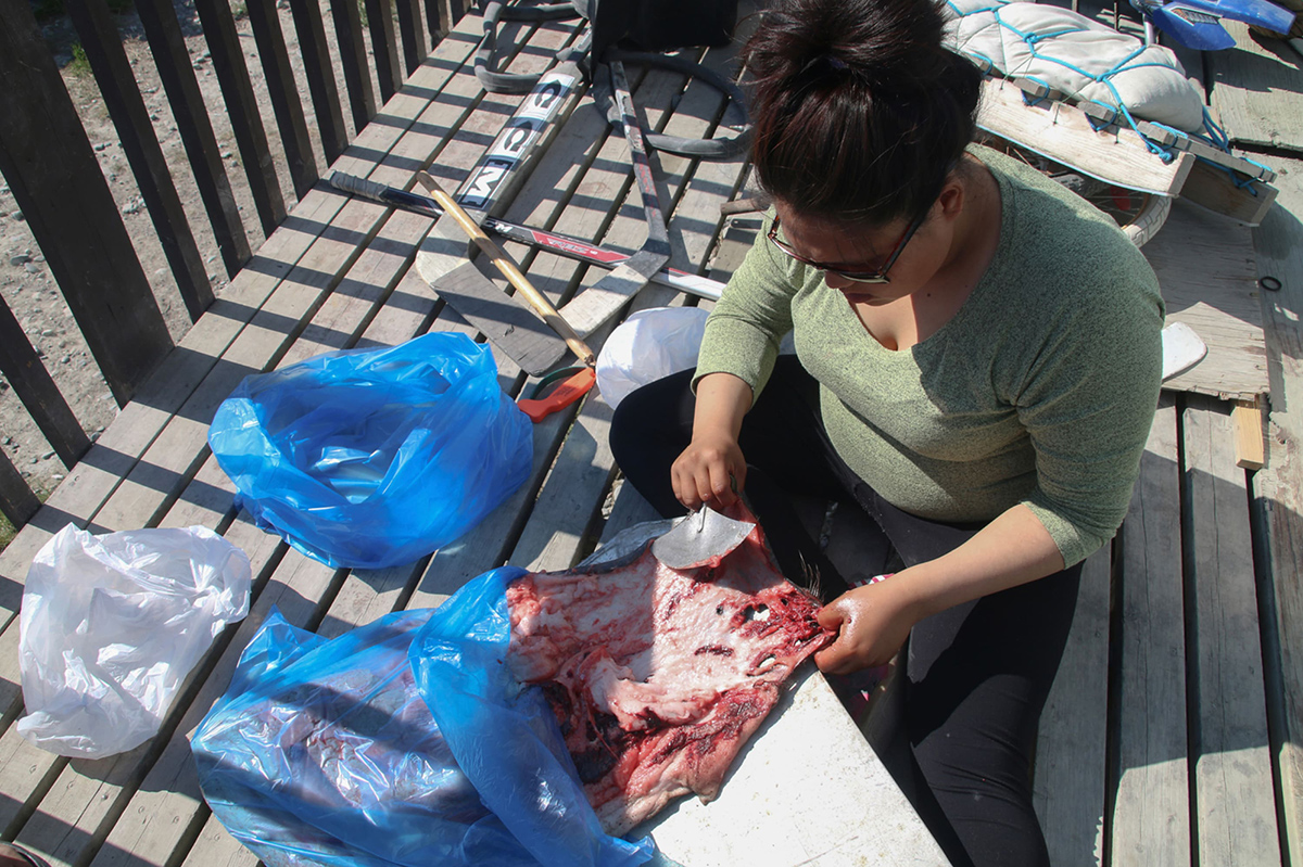 A woman shovelling meat into a blue plastic bag