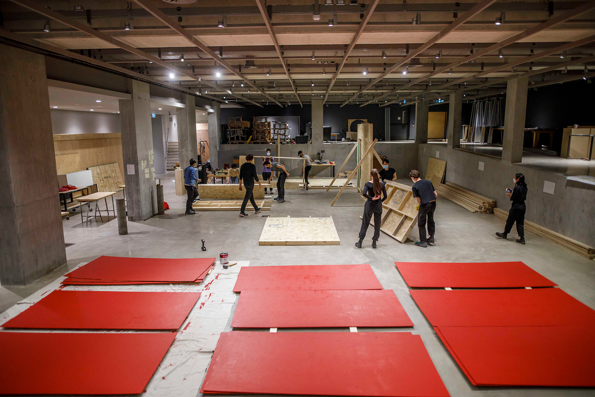 Daniels architecture students are working on building a station in the background; nine large red panels are laid out on the floor in the foreground