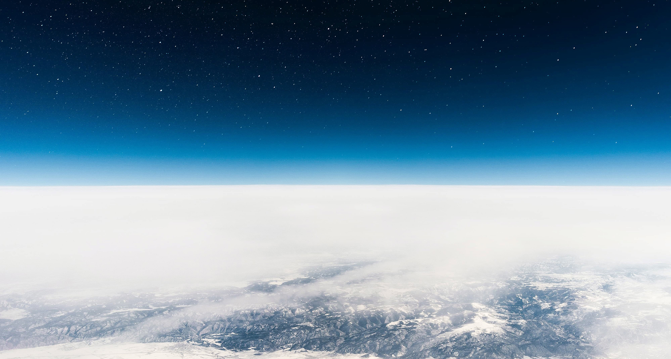 Outer space above and the white and blue surface of the Earth below