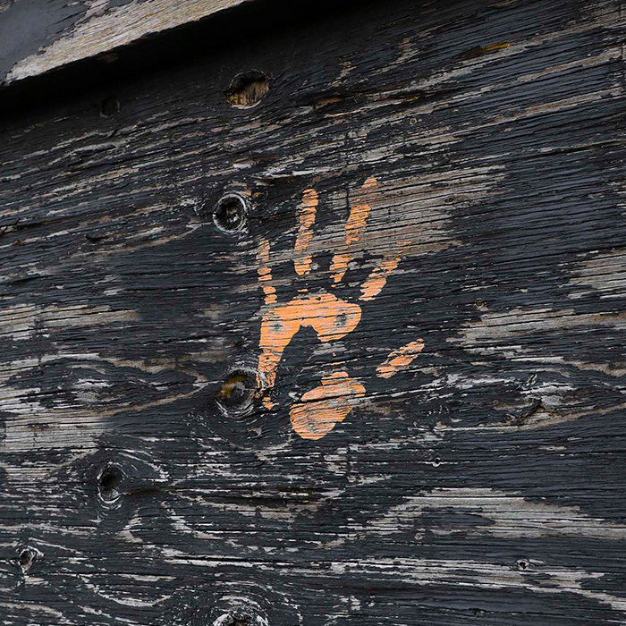 Orange hand print painting on the side of a wooden wall