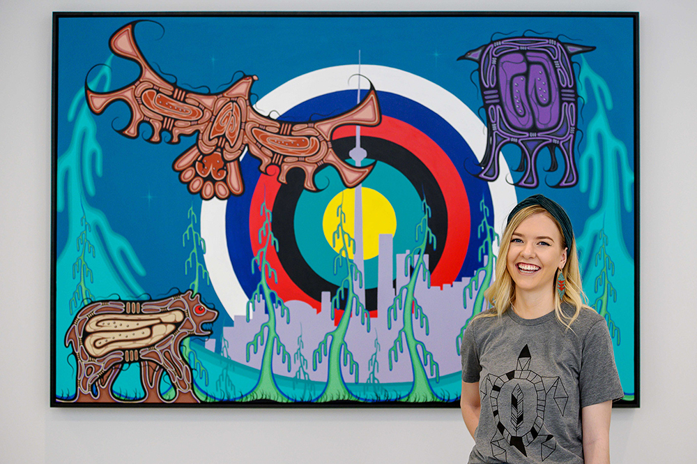Karlie Nordstrom standing in front of an Indigenous painting of animals and trees in the foreground and the outline of a city and concentric circles of different colours in the background