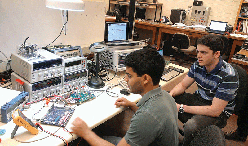 Two Brazilian engineering students in a lab, working on electronic circuits