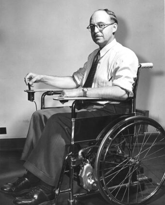 Black and white photo of George Klein sitting in an electric wheelchair