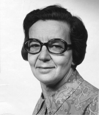 Black and white photo of Ursula Franklin wearing dark plastic-framed glasses and a patterned, collared shirt
