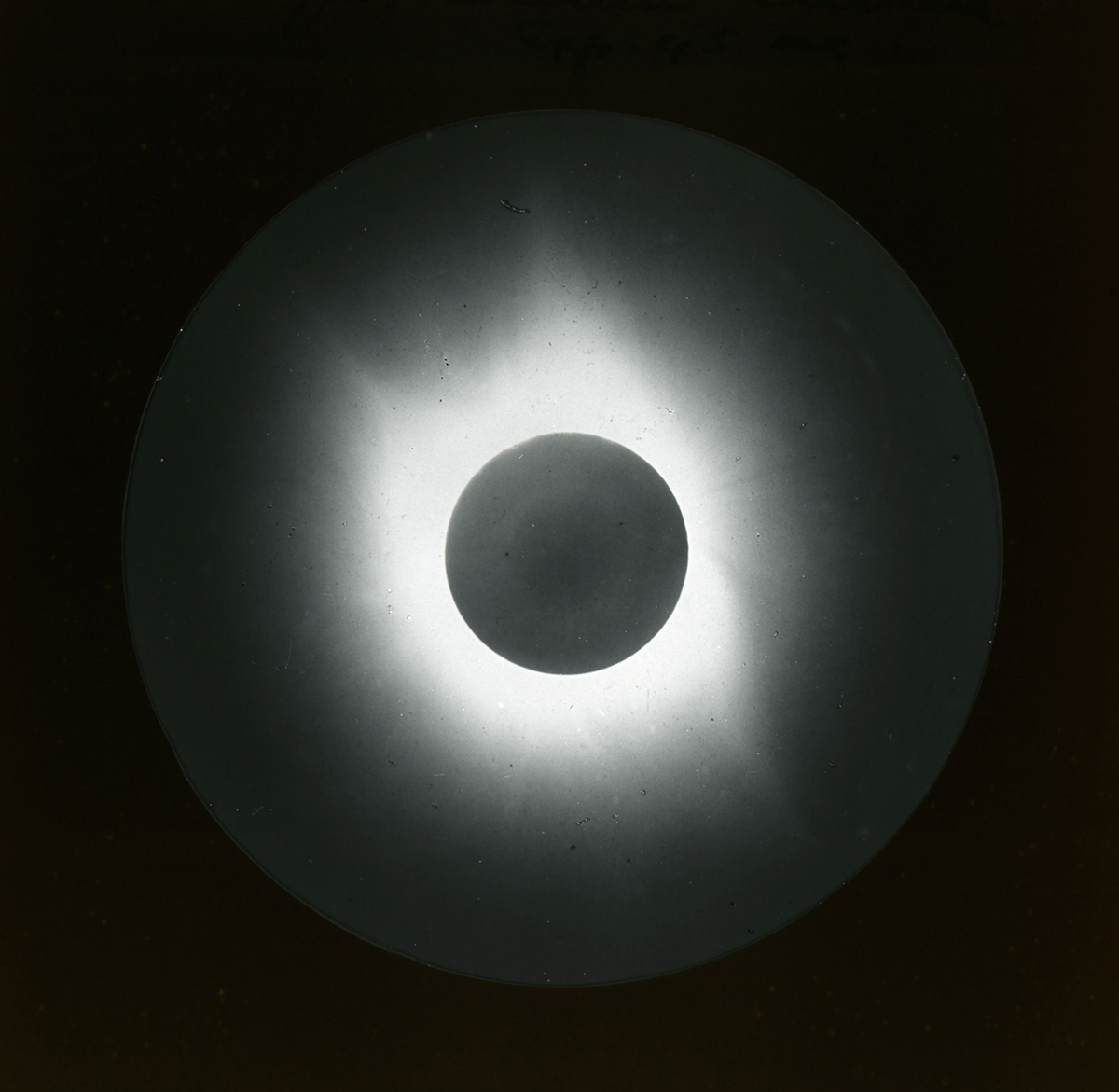 Black and white photo of the glowing white corona around the sun, which appears as a round dark disc, captured by the Einstein Camera during a total eclipse