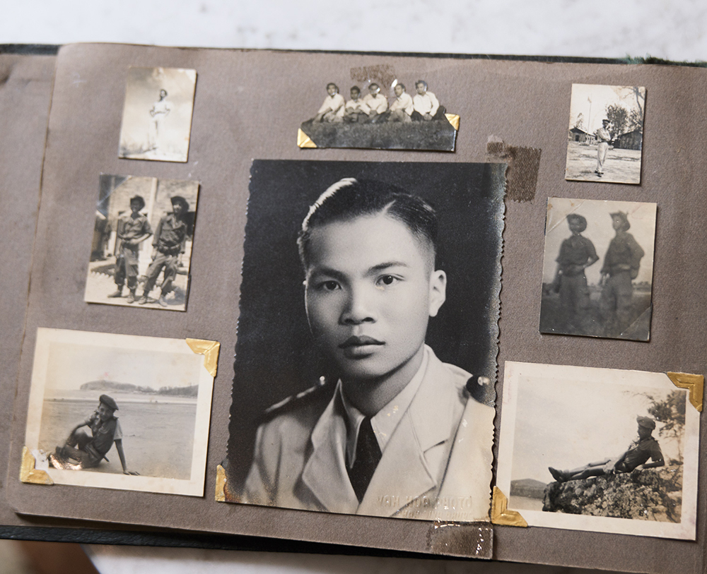 Black and white photos of varying sizes, depicting Vietnamese soldiers alone, in pairs or in a group. The photos are laid out on the pages of an old photo album, with the largest photo - a headshot of a young soldier in uniform - placed in the centre.