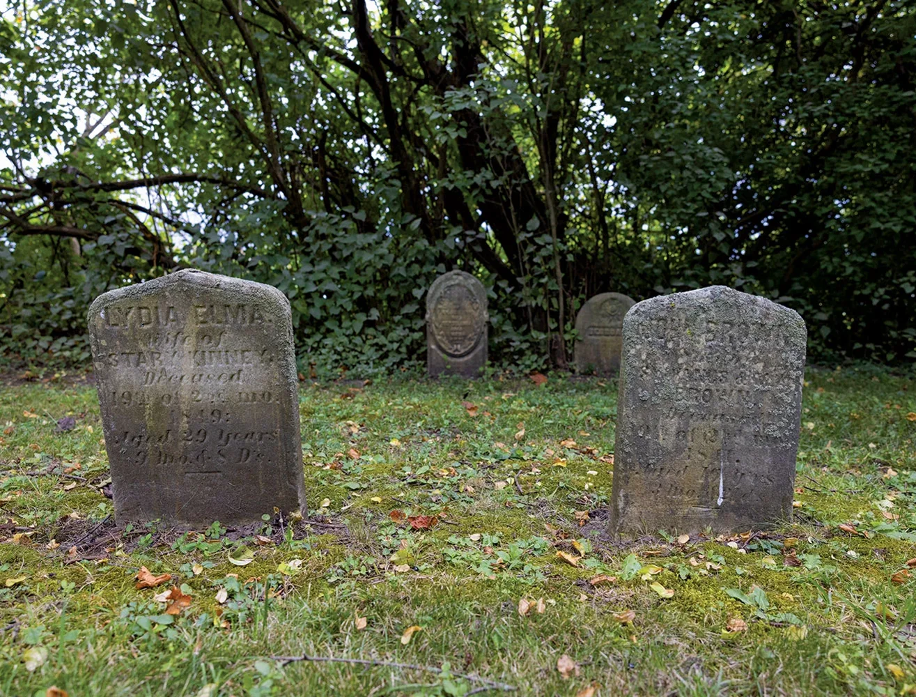 Close up shot of two weathered tombstones in a cemetery