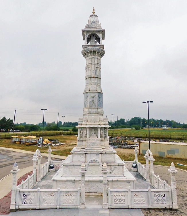 A tall pillar made of white marble with traditional Indian carvings