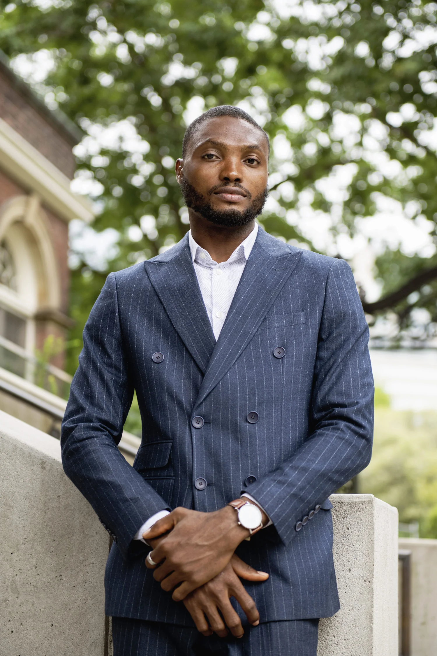 Outdoor photo of Mathew Okwoli in a blue, pin-striped, double-breasted suit