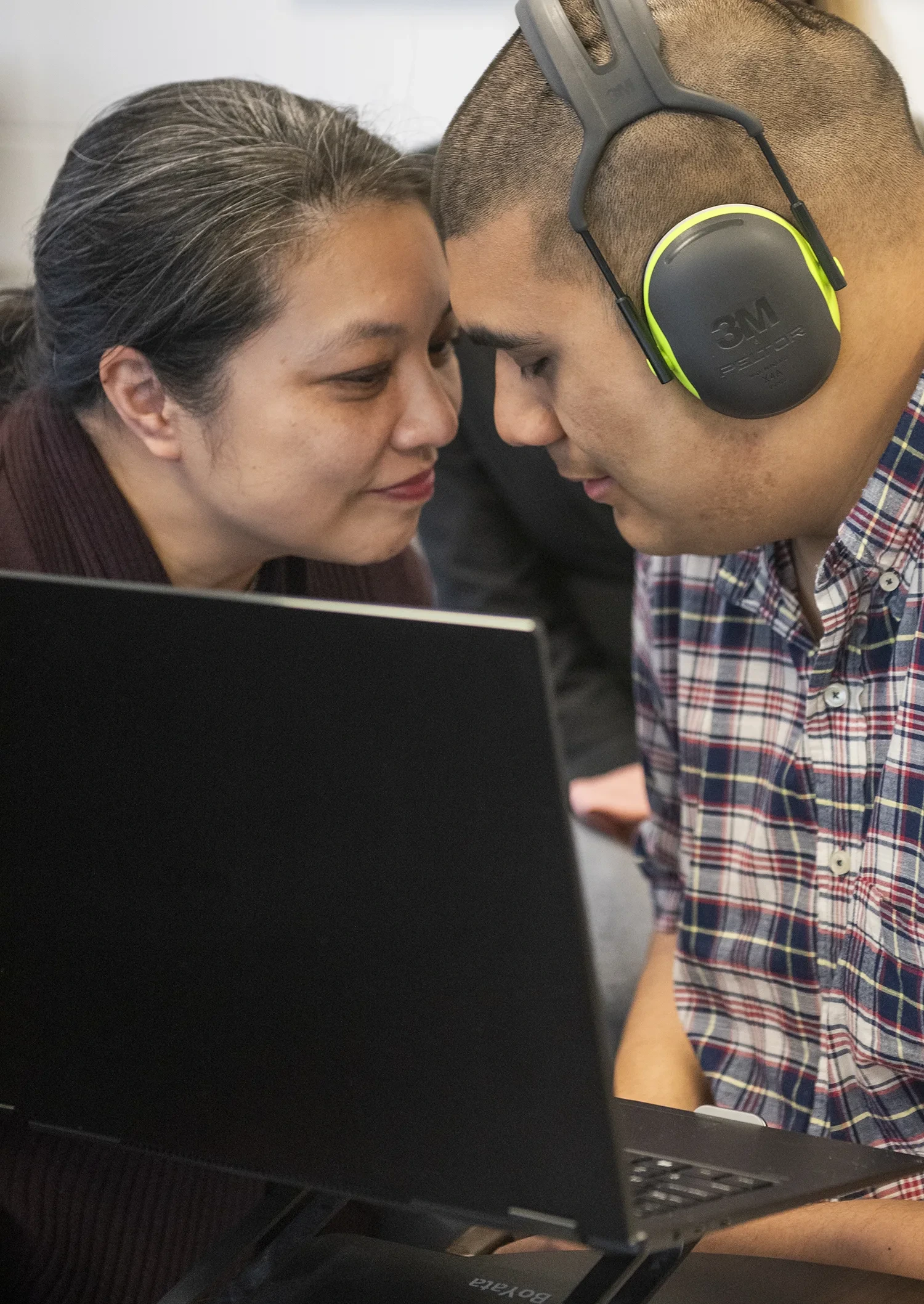 Isaiah Grewal and his mother Melody in an intimate moment, sitting with foreheads nearly touching in front of a laptop