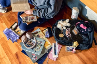 Items on the floor including latex gloves, drug testing kit with vape pens, fuzzy dog and photo frame keychains, and a laptop and iPad with stickers