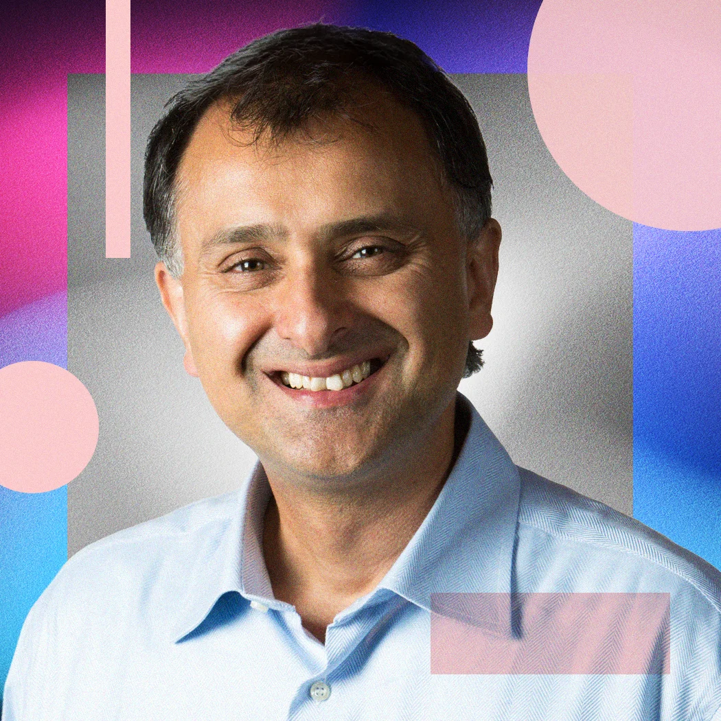 Rotman School of Management professor Ajay Agrawal smiles at the camera against a colourful abstract background.